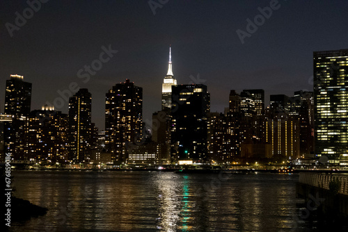 Scenic view of coastline skyscrapers with illuminated lights at night in New York