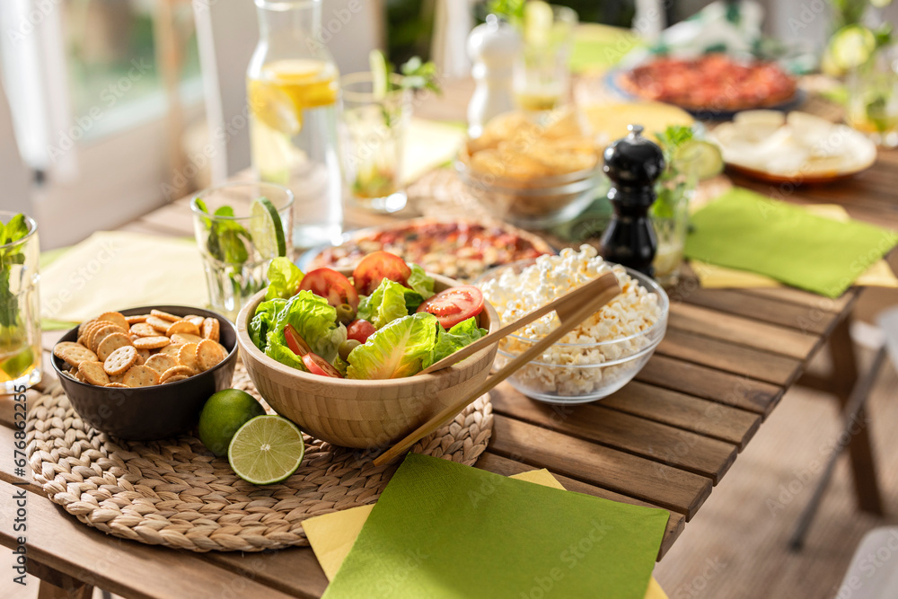 Colorful close-up photograph of a table with the focus on a salad and an assortment of food in the background