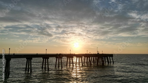 Beautiful sunset over a pier in the sea. © Wirestock