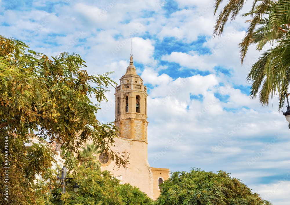 Against a background of blue sky, palm trees and plants - view of the Church of St. Bartholomew and Santa Tecla in Sitges, Catalonia, Spain. Against a background of blue sky, palm trees and plants - view of the Church of St. Bartholomew and Santa Tecla in Sitges, Catalonia, Spain.