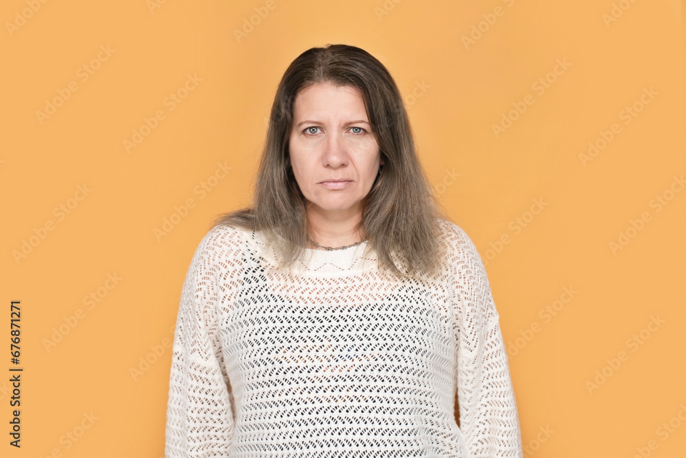 Cute but sad middle-aged woman on yellow background, woman's hair starts to deteriorate, turns gray and falls out, woman needs special vitamins for hair growth, health and beauty concept after 45 Cute but sad middle-aged woman on yellow background, woman's hair starts to deteriorate, turns gray and falls out, woman needs special vitamins for hair growth, health and beauty concept after 45