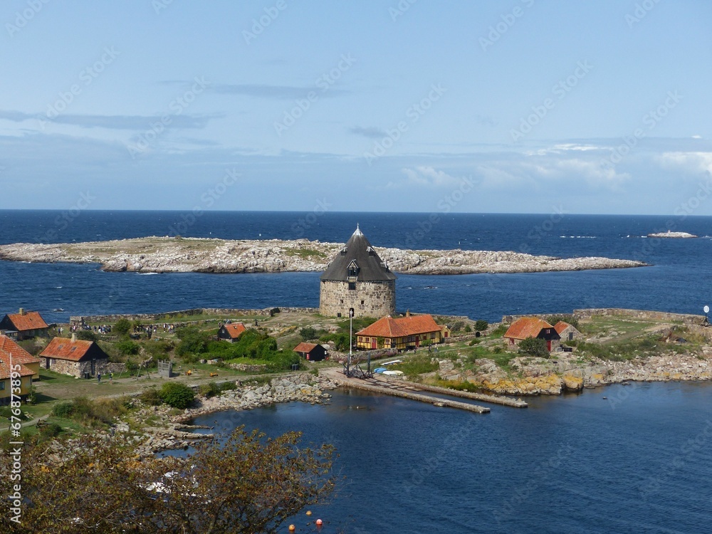 Aerial shot of a stone building on the coastline of Bornholm Island with clouds in the background