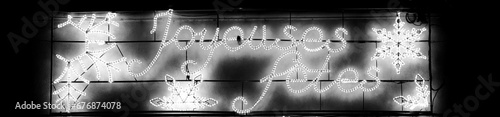 Joyeuses fêtes winter holidays glowing decoration at city billboard. France. Happy holidays greeting in French. Black white istoric photo photo