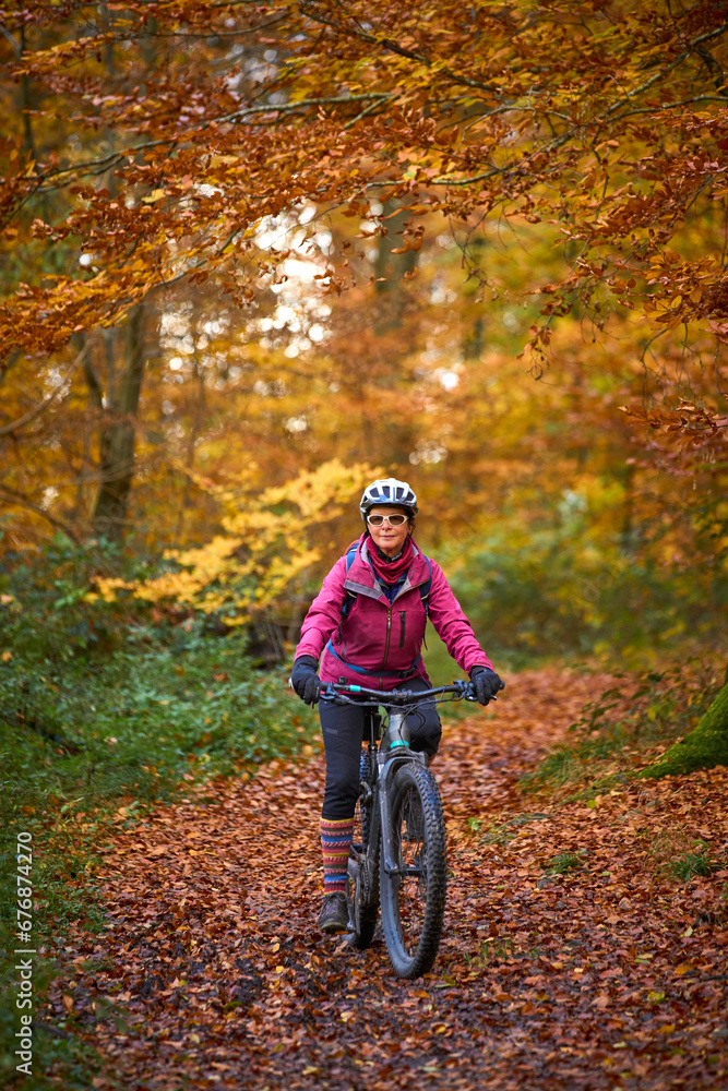 Fototapeta premium nice senior woman riding her electric mountainbike on the autumnal forest trails near Stuttgart,Baden-Wuerttemberg, Germany