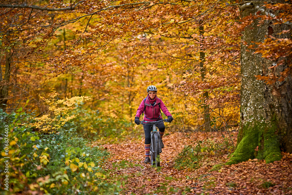 nice senior woman riding her electric mountainbike on the autumnal forest trails near Stuttgart,Baden-Wuerttemberg, Germany nice senior woman riding her electric mountainbike on the autumnal forest trails near Stuttgart,Baden-Wuerttemberg, Germany