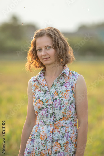 Portrait of a young beautiful girl in a light dress on a summer field.