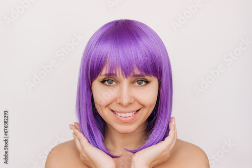 Young smiling woman with the dyed deep purple hair isolated on light background. Result of coloring. Bright saturated extravagant color. Beauty and fashion. Colored bright wig with square and bangs