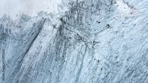 Aerial top view of blue alpine glacier texture and crevasses