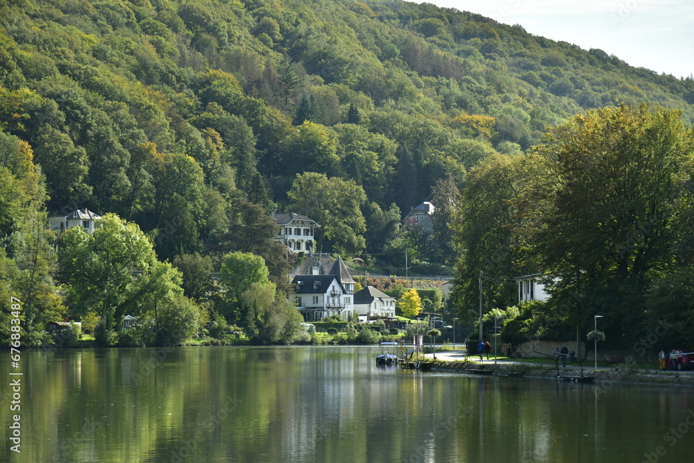 Effet miroir de la Meuse traversant un environnement bucolique et forestier avec quelques maisons parfois dissimulée dans la nature luxuriante à Lustin Effet miroir de la Meuse traversant un environnement bucolique et forestier avec quelques maisons parfois dissimulée dans la nature luxuriante à Lustin