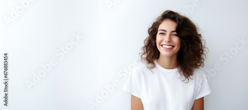 portrait of a beautiful young happy woman laughing. a smiling woman wearing white sweater standing and smiling on gray background with copy space. photo