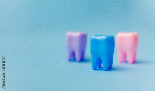 Three multi-colored tooth models on a blue background. Concept of dental health. Flat lay, copy space for the text. Dentistry. Place for text. Oral health and dental examination of teeth. Dentistry. photo