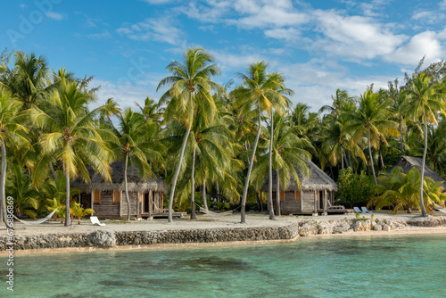 French Polynesia Tikehau atoll with sandy beach, beach bungalows, palm trees and blue sky. photo