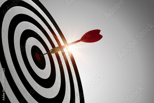 Red dart with reflected light hitting the center of the dartboard, concept of reaching the specified target and winning goals business concepts. photo