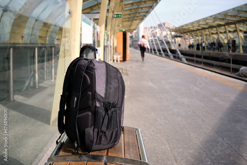 A lost or forgotten backpack on a bench on an open platform of a city metro.