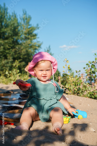 Cute baby child girl in cotton cape and panama enjoys summer beach