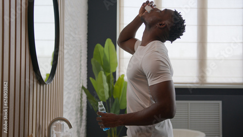 Bild auf Leinwand African American man cleaning teeth rinse with dental care product mouth hygiene