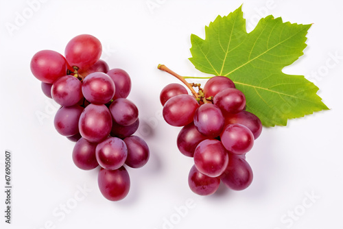 Half-sliced red grapes with verdant foliage isolated on a pristine backdrop, viewed from above.