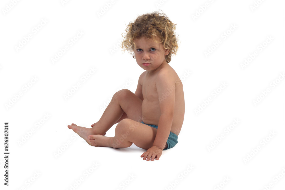 the angry baby boy sitting on the floor on white background the angry baby boy sitting on the floor on white background