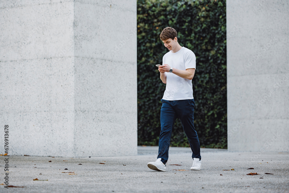 Young adult student using smart phone while going to school campus. Connected with friends everywhere, checking online bank, posting stories. Young adult student using smart phone while going to school campus. Connected with friends everywhere, checking online bank, posting stories.