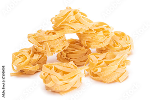 A Pile of Classic Italian Raw Egg Fettuccine - Isolated on White Background. Dry Twisted Uncooked Pasta. Italian Culture and Cuisine. Raw Golden Macaroni Pattern - Isolation