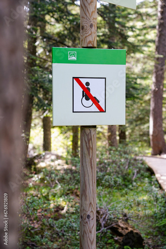 disability sign with a crossed out wheelchair in the forest. Universal accessibility conceptual pictogram. No passing