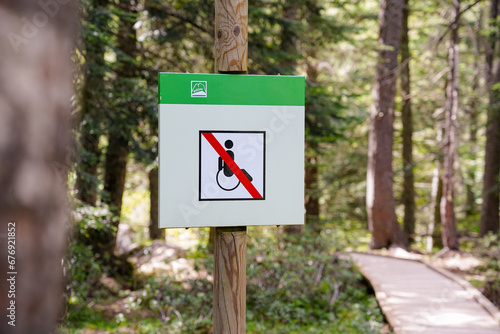 disability sign with a crossed out wheelchair in the forest. Universal accessibility conceptual pictogram. No passing