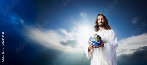 Jesus the son of God in white clothes stands at a background of blue sky and clouds - he is smiling and holding the planet Earth globe in his hands. Jesus loves you. Wide image. photo