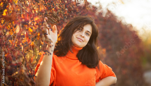 beautiful happy girl standing near colorful autumn leaves. romantic pretty woman looking at camera