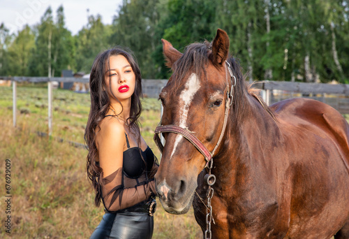Beautiful young caucasian woman standing near the horse.