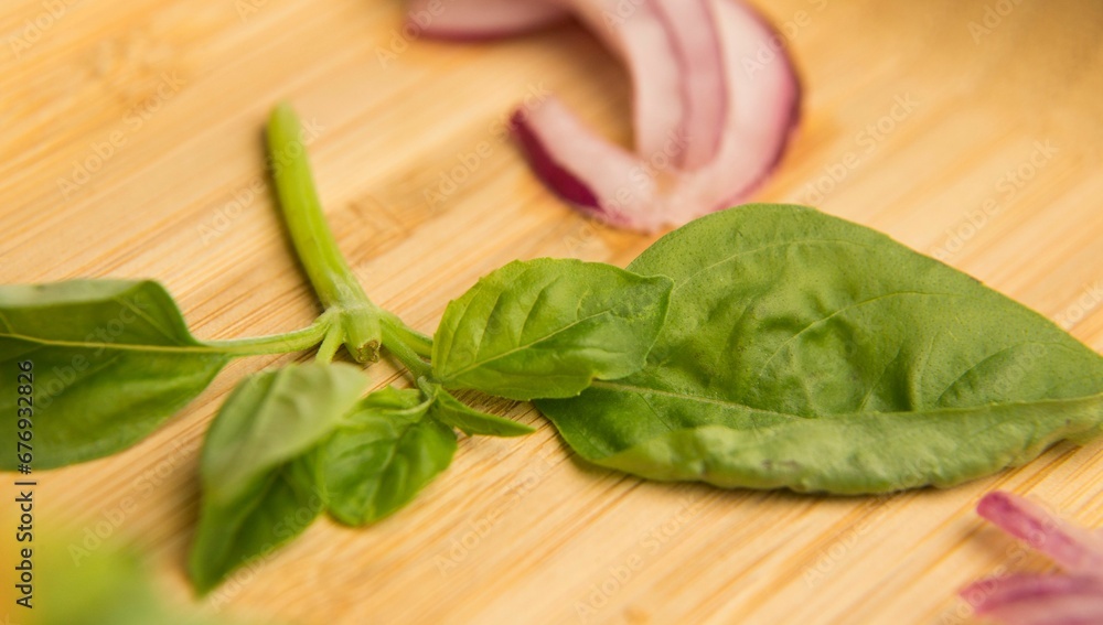 Closeup of cut onion and leaves on a wooden plate Closeup of cut onion and leaves on a wooden plate
