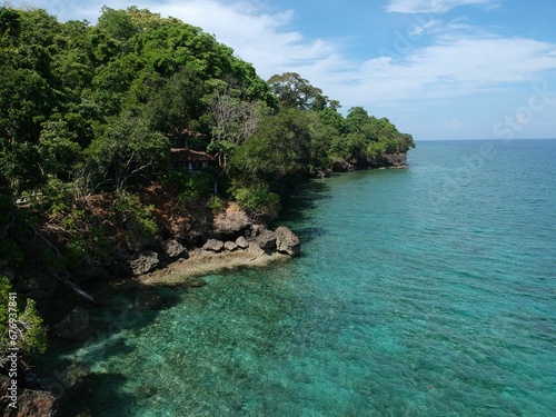 a sandy beach with clear blue water and trees around it