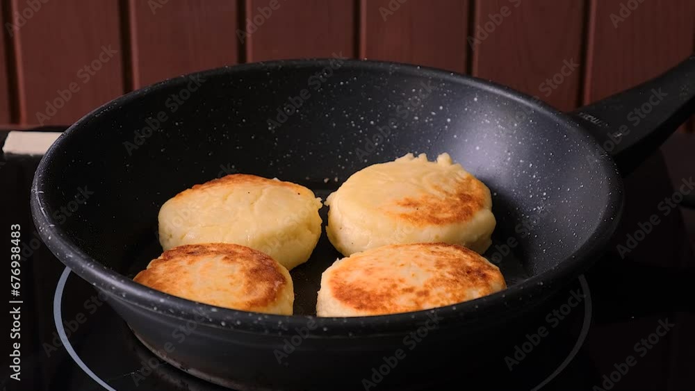 the cook turns over the cheesecakes that are fried in a frying pan. women's hands make syrniki. the cook turns over the cheesecakes that are fried in a frying pan. women's hands make syrniki.