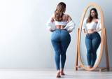 Pretty plus size woman looking into a mirror - Acceptance and inclusion - white blouse and blue jeans