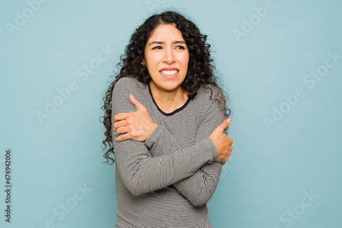 Hispanic woman feeling very cold with shivers during cold weather photo