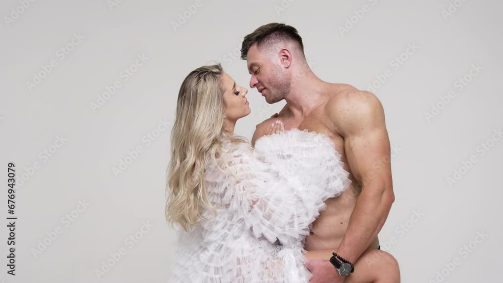 Sporty topless Caucasian man and blonde woman in white blouse. Couple in love studio footage. White backdrop. Sporty topless Caucasian man and blonde woman in white blouse. Couple in love studio footage. White backdrop.