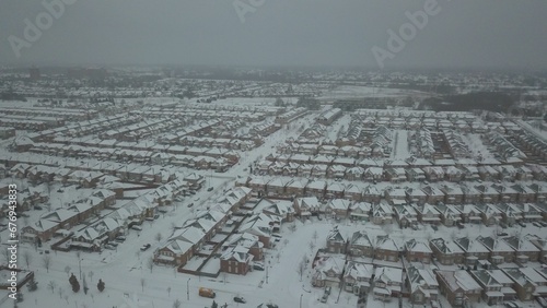 High angle shot of several houses, a road and cars during winter, covered with snow
