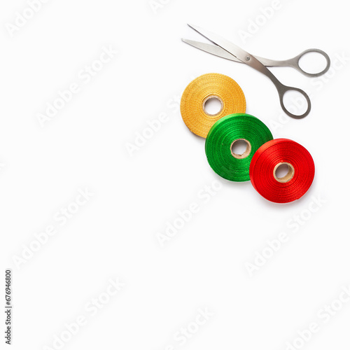 Set of colorful satin ribbon spools and scissors on white background. Top view