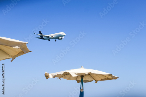 the plane lands over the sea, the beach. The plane flies over the beach umbrellas