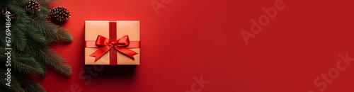 Gift box with a red bow on a red background. Christmas decorations with spruce branches with cones. Festive background. High quality photo