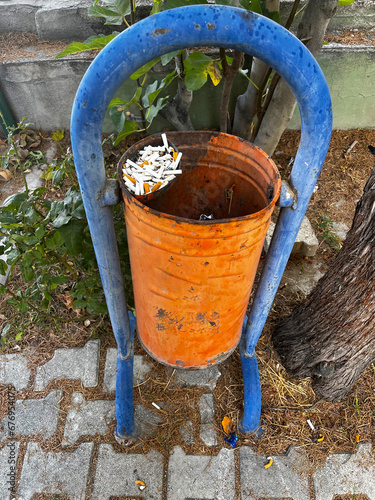 Old trash can with cigarette butts in it.