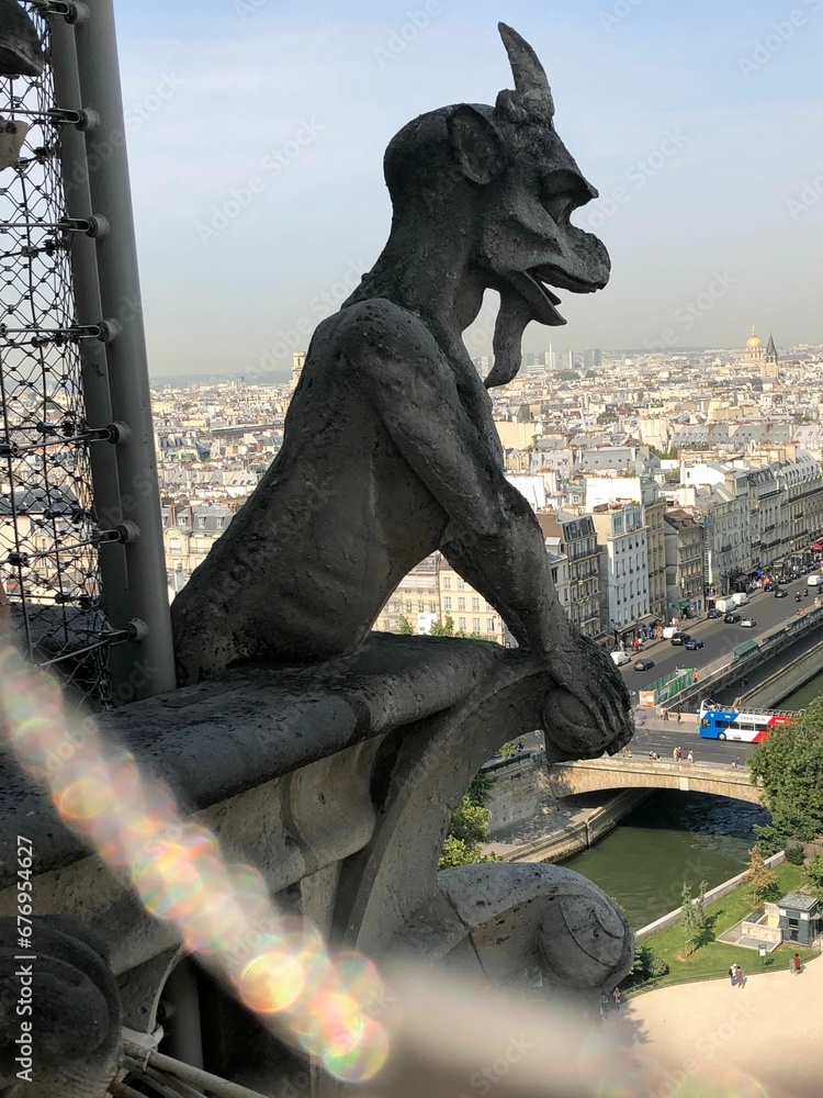 Vertical shot of a gargoyle of Notre Dame de Paris with cityscape in the background
