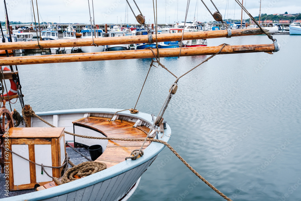 Detail of a wooden and elegant sailboat docked in port.