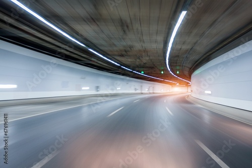 Motion blur shot of an empty road under a tunnel with white lights photo
