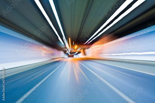 Motion blur shot of an empty road under a tunnel with white lights
