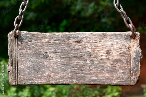 Tábua de madeira suspensa por correntes de metal. Placa de madeira envelhecida. Painel de madeira velha. photo