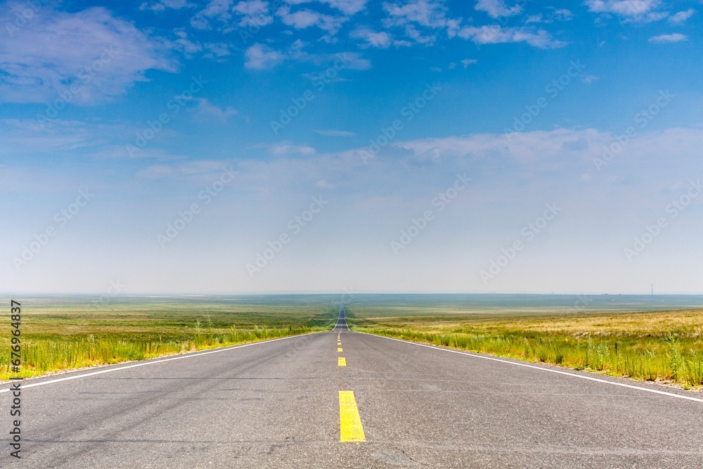 Beautiful shot of a road between green fields in the daytime Beautiful shot of a road between green fields in the daytime