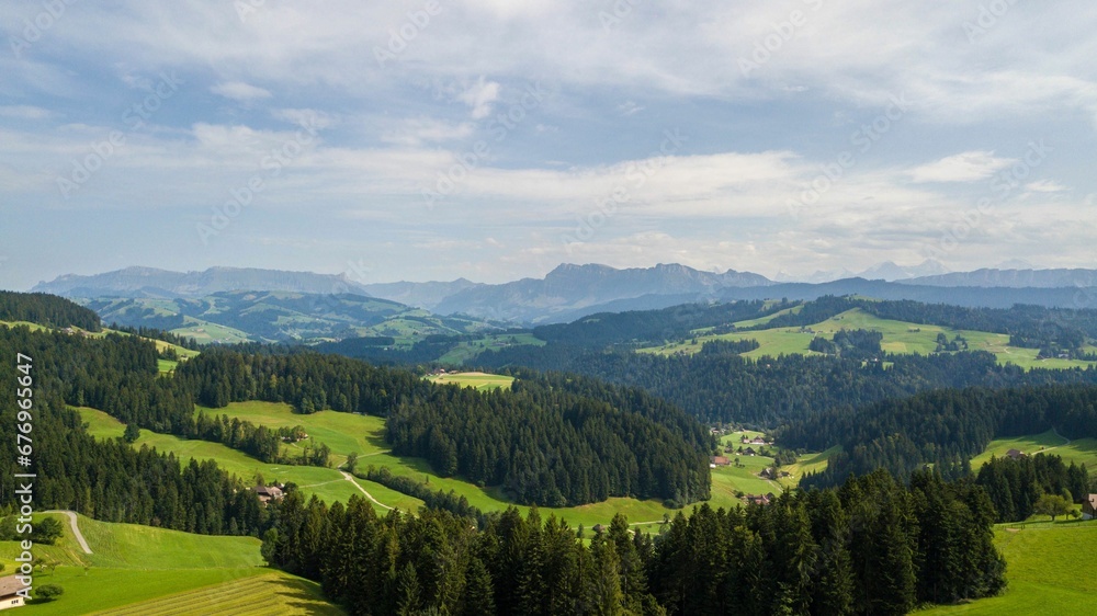 Aerial view of lush green valleys and trees near mountains in Emmental, Switzerland