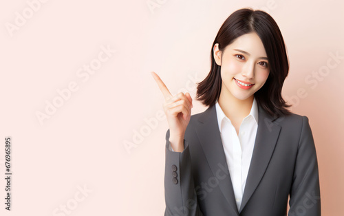 New idea, opinion, thought concept. A bussinesswoman with suits shows her index finger to point the upper side of the image on a pink background. Copy space for text, advertising, message, logo