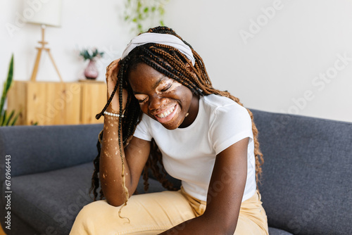 Joyful young african woman laughing sitting on sofa at home. Happiness, diversity and people concept. photo