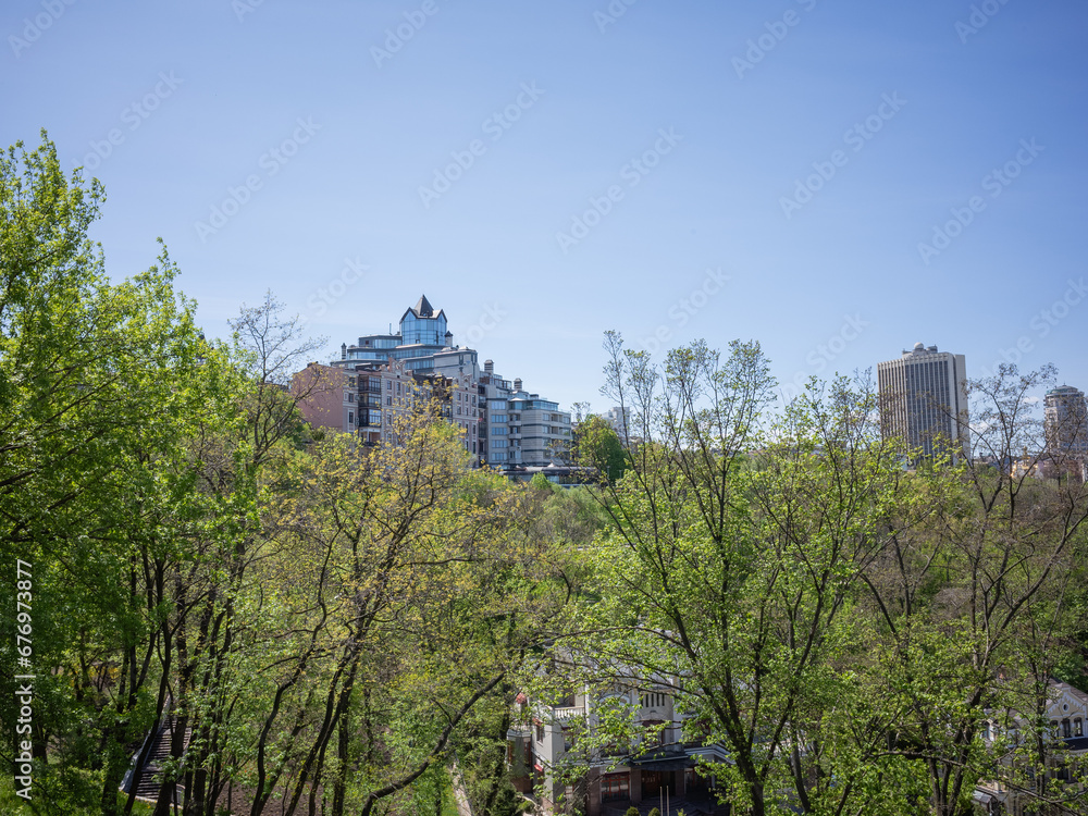 cityscape and public park surrounded by green trees in sunny day